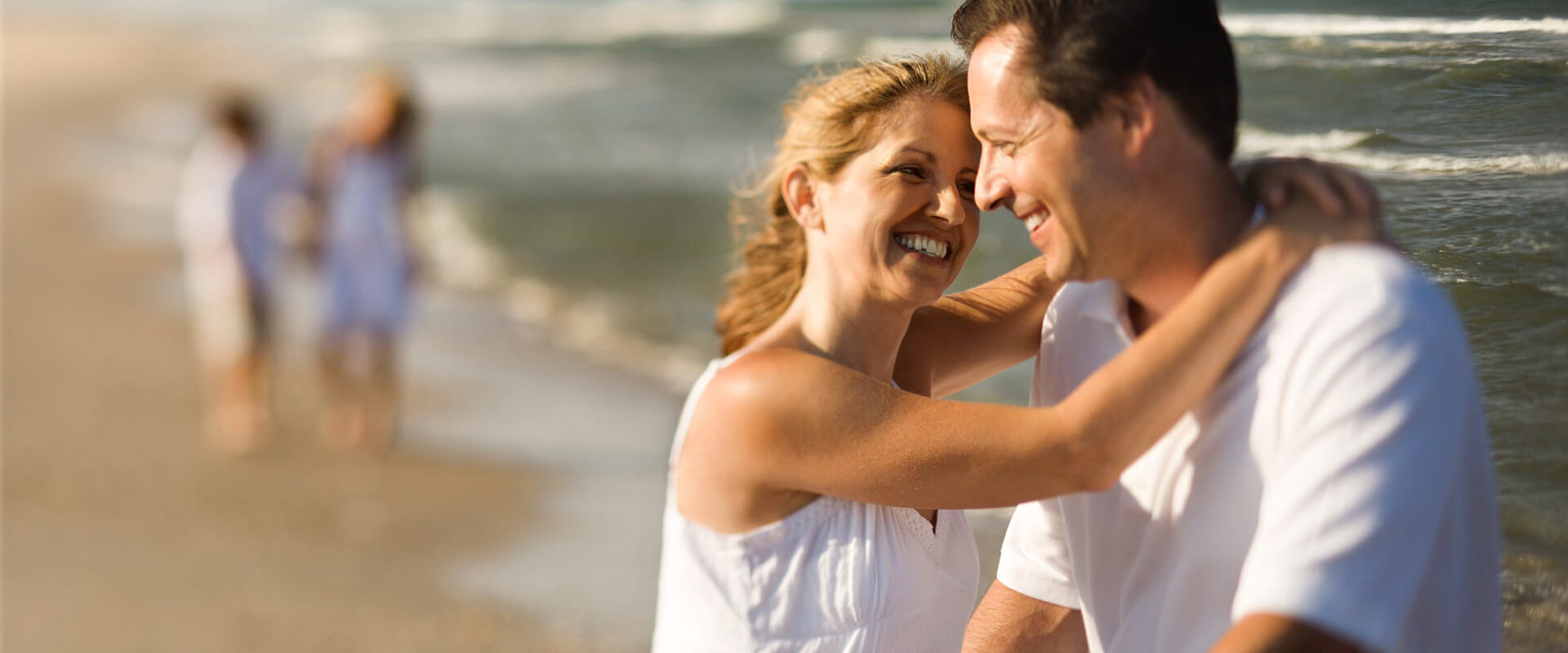 A couple laughs together on the beach. They are happy with their decision to pursue couples therapy or marriage counseling in Forest Hills, NY with marriage counselor Deborah Karnbad.