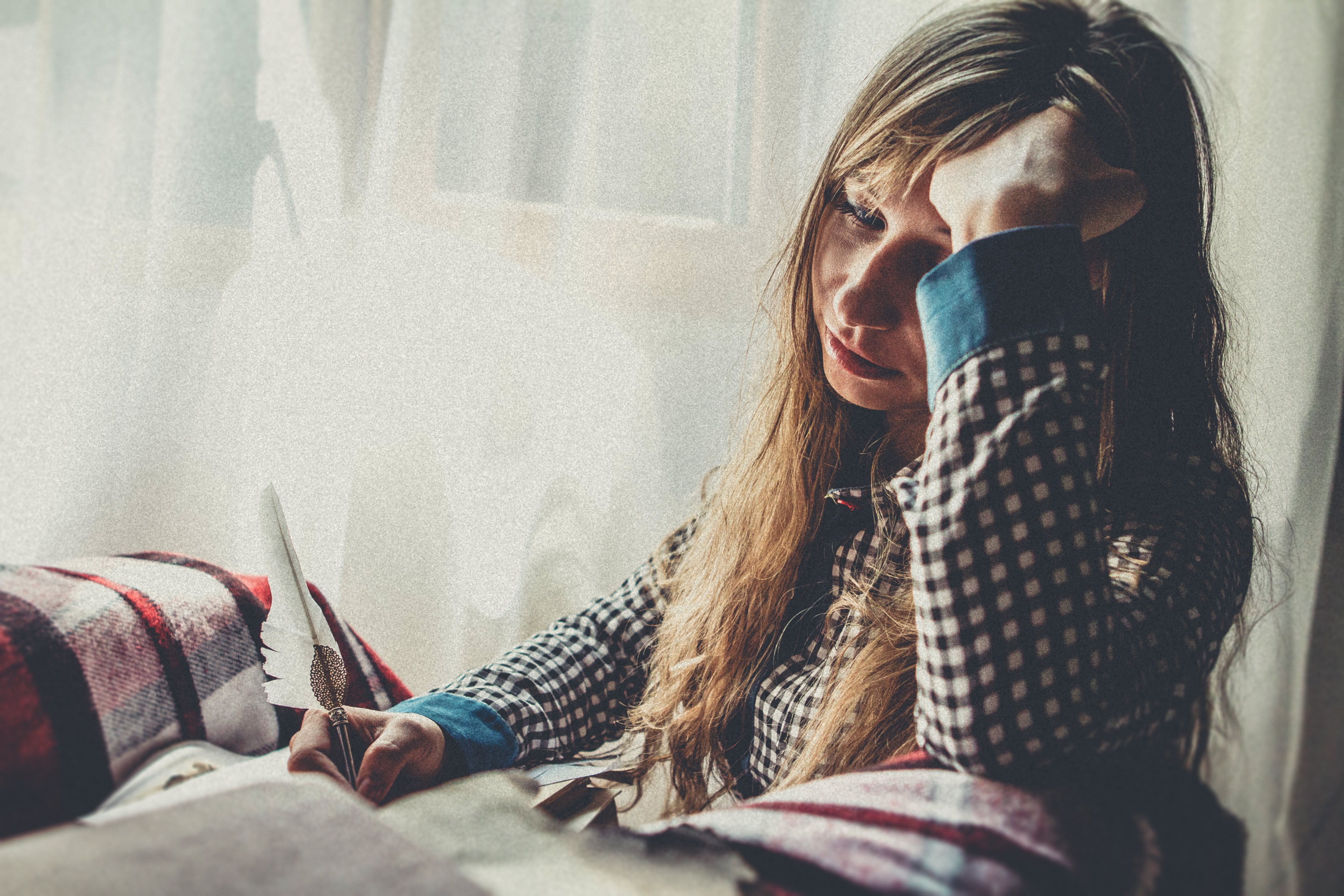 A woman sits at a table looking overwhelmed. She can't wait to begin her online session for counseling for stress in New York with Deborah Karnbad.