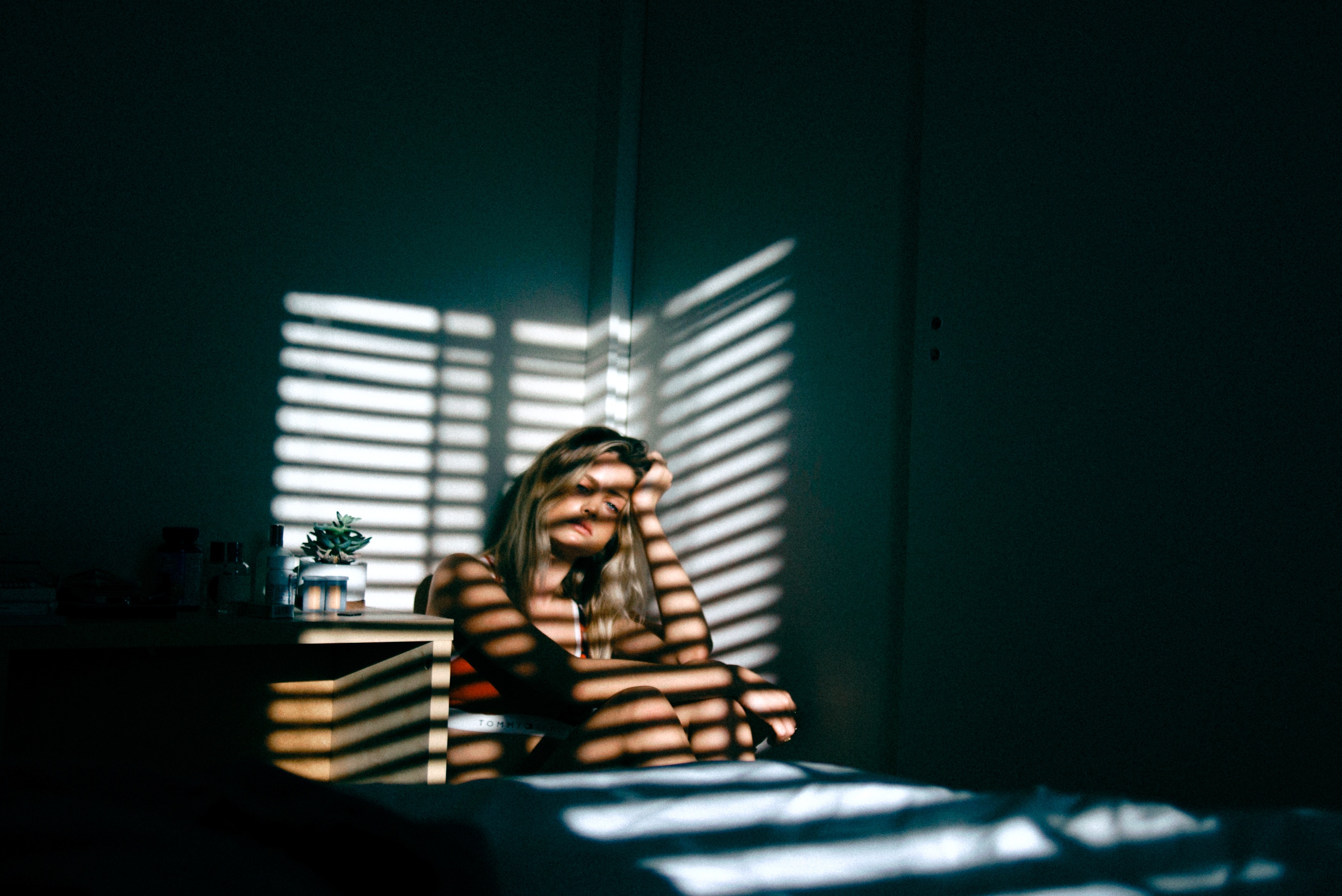 A girl sits alone at a table, looking sad. She is waiting to start grief counseling in Forest Hills, NY with grief counselor Deborah Karnbad.