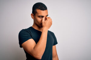 A young man puts his hand to his face in distress. He has decided to start anxiety therapy in Forest Hills, NY with Deborah Karnbad. 