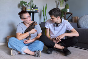 A mom and son play with their dog. She is feeling stressed out as a COVID parent so she has started counseling for parents in Long Island, NY with parent counselor Deborah Karnbad.