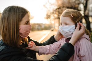 A mom helps her daughter put on a mask. This reflects concepts discussed in an online support group in New York with Deborah Karnbad. You can get online therapy in New York for frustrated women, overwhelmed moms and more here!