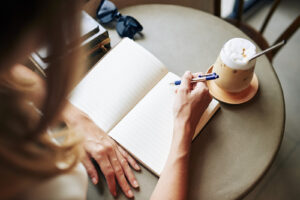 A woman is writing in a journal. This demonstrates concepts of trauma therapy in Forest Hills, NY. 